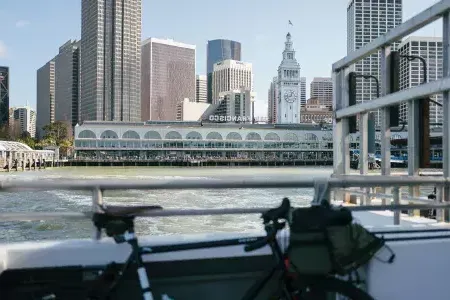 Bicicleta encostada em um trilho com o Ferry Building ao fundo.