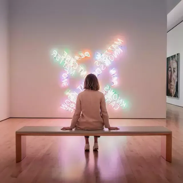 Una mujer, sentada en un banco, mira una obra de arte luminoso contemporáneo en el SF MOMA de San Francisco.